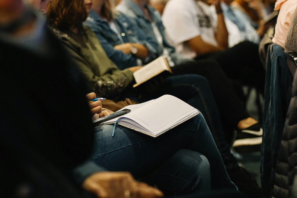 A row of people sat with pens and notebooks.